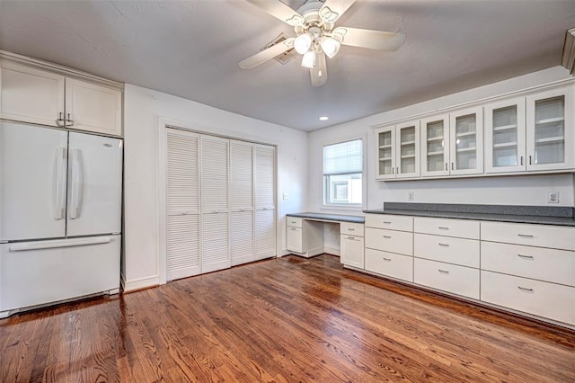 kitchen featuring dark wood-style floors, dark countertops, glass insert cabinets, and freestanding refrigerator