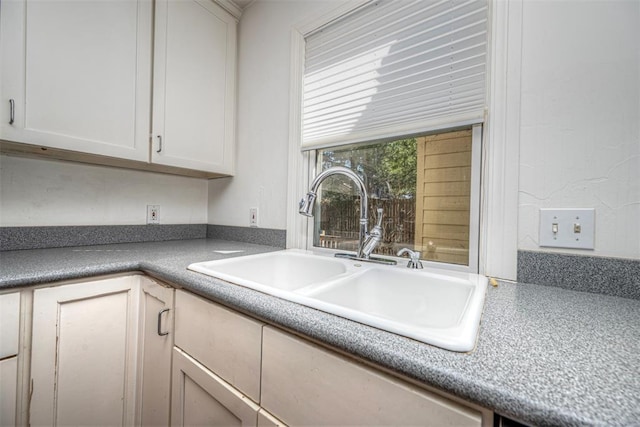 kitchen featuring white cabinetry and a sink