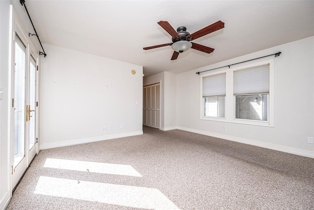 carpeted spare room with baseboards and a ceiling fan