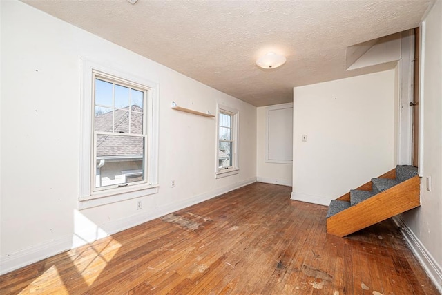 spare room with stairway, baseboards, and wood-type flooring