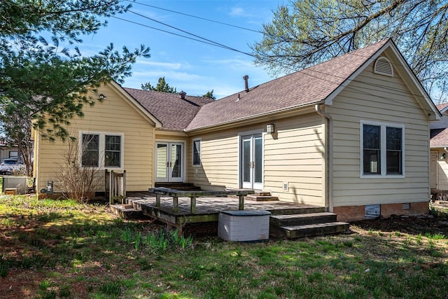 rear view of property featuring a shingled roof, french doors, crawl space, a deck, and a lawn