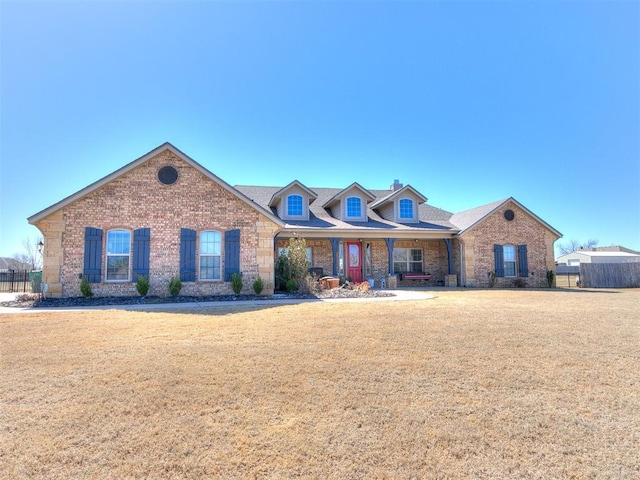 view of front of house featuring brick siding, a front lawn, and fence