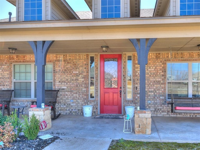 entrance to property featuring brick siding and covered porch