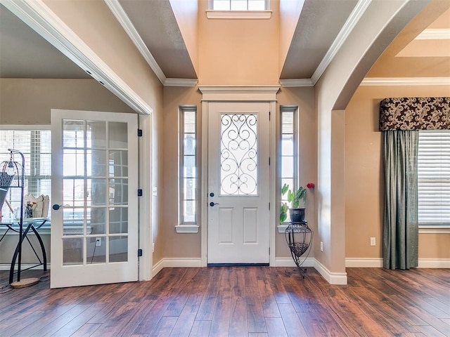 foyer featuring arched walkways, hardwood / wood-style flooring, baseboards, and ornamental molding