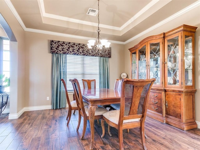 dining area featuring visible vents, a tray ceiling, wood finished floors, arched walkways, and a notable chandelier