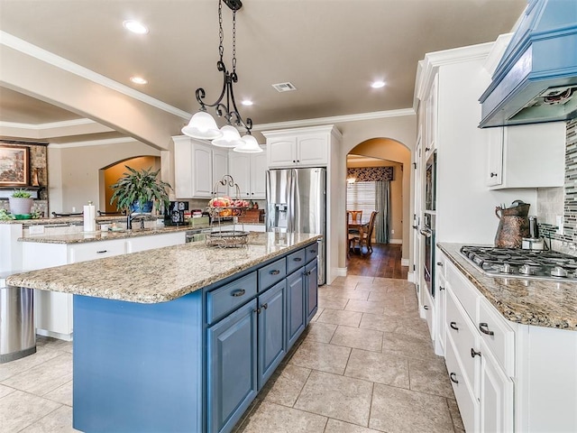 kitchen featuring premium range hood, blue cabinetry, a kitchen island, white cabinetry, and arched walkways