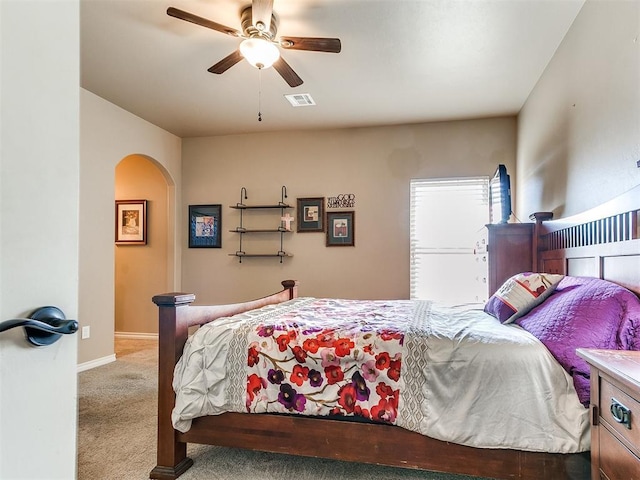 carpeted bedroom featuring a ceiling fan, baseboards, visible vents, and arched walkways