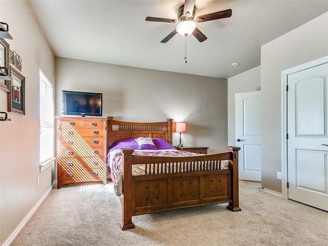 bedroom with light colored carpet, baseboards, and ceiling fan