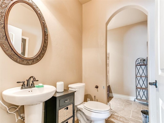 half bathroom featuring baseboards and toilet