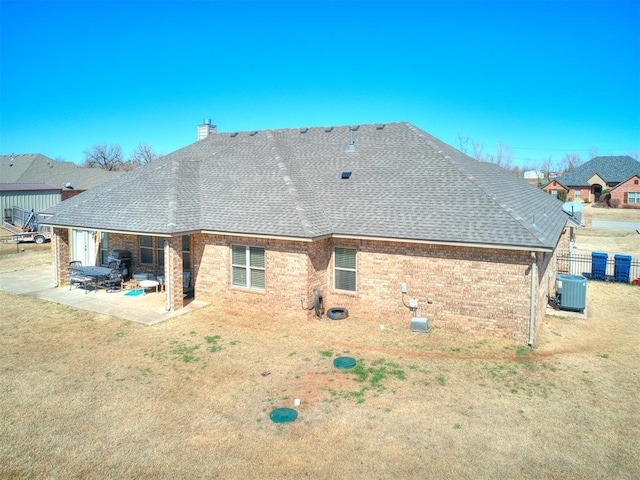 back of house featuring brick siding, a patio, and roof with shingles