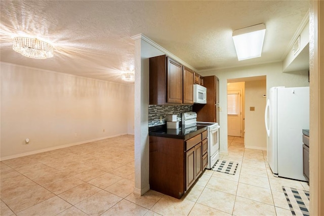 kitchen with dark countertops, backsplash, crown molding, light tile patterned flooring, and white appliances