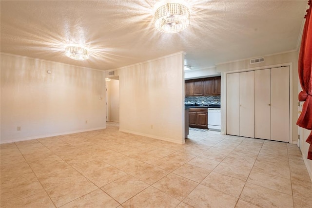 spare room featuring a textured ceiling, visible vents, a chandelier, and ornamental molding