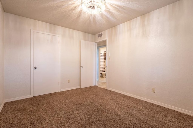 unfurnished bedroom featuring visible vents, baseboards, carpet flooring, a notable chandelier, and a textured ceiling