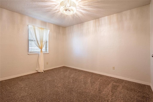 carpeted spare room featuring an inviting chandelier, a textured wall, baseboards, and a textured ceiling