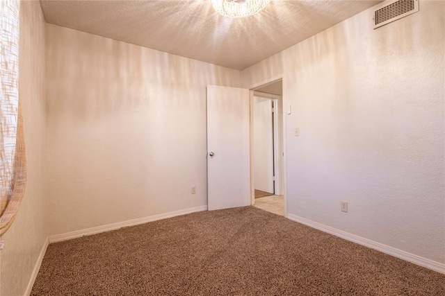 unfurnished room with visible vents, baseboards, carpet, and a textured ceiling