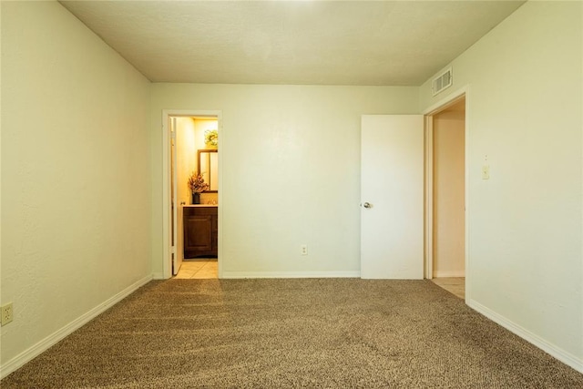 spare room with visible vents, light colored carpet, and baseboards