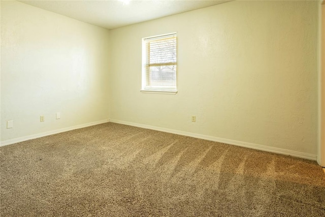 carpeted spare room featuring baseboards