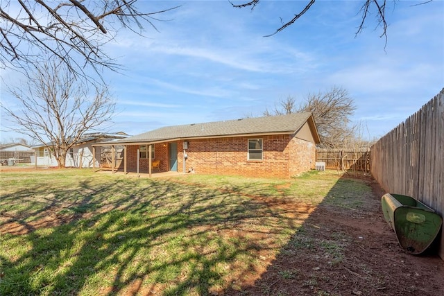 back of house with a patio area, a yard, a fenced backyard, and brick siding