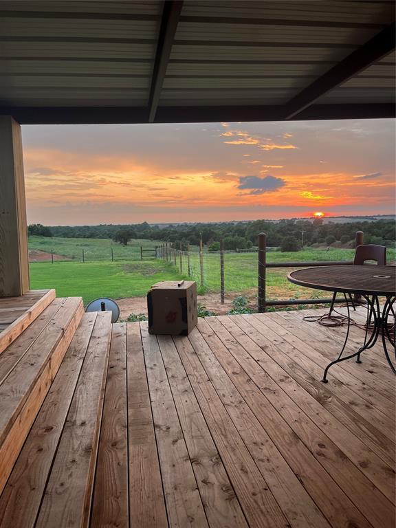 deck at dusk with a rural view and a lawn