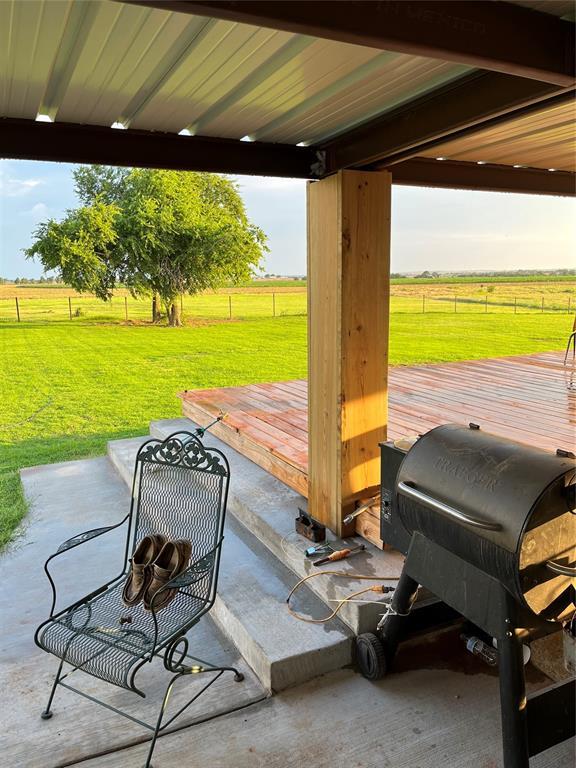 view of patio featuring a rural view, a grill, a wooden deck, and fence