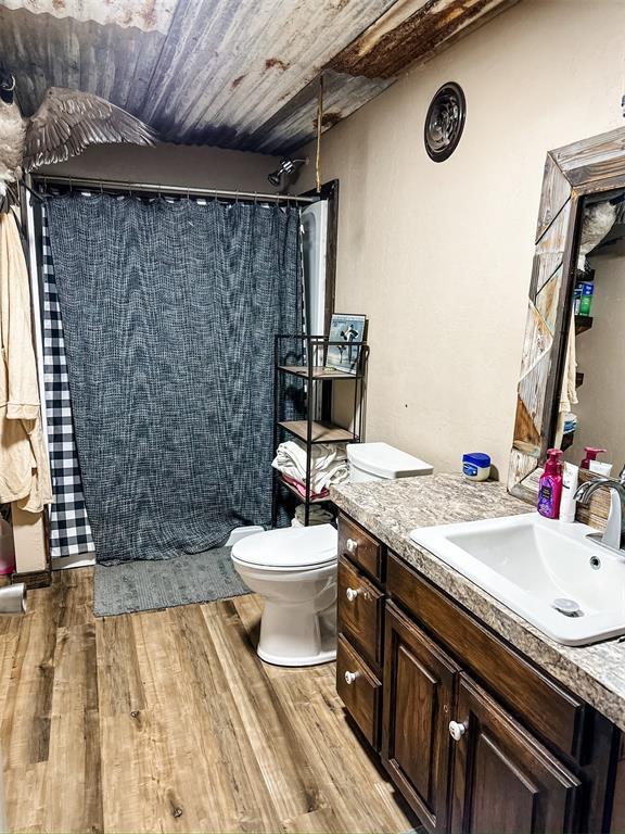 full bath featuring vanity, wood finished floors, a tile shower, wood ceiling, and toilet