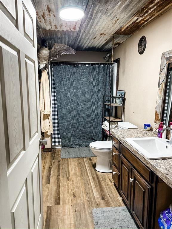 full bathroom with vanity, wood finished floors, tiled shower, wood ceiling, and toilet