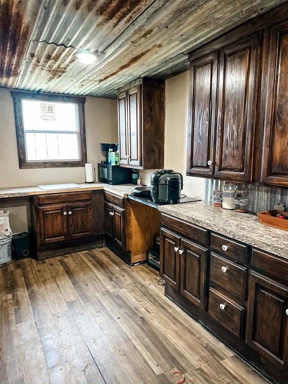 kitchen featuring dark brown cabinets, wood ceiling, light countertops, built in desk, and wood finished floors