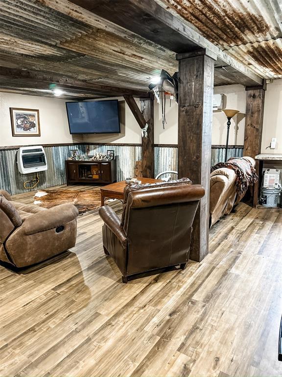 living room with heating unit, wood ceiling, wood finished floors, and wainscoting