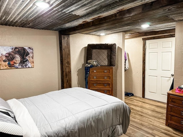 bedroom featuring light wood-style floors, wood ceiling, and a textured wall