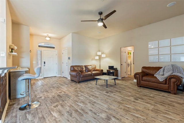 living room featuring washer / clothes dryer, wood finished floors, and ceiling fan