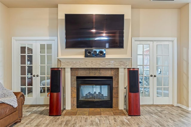 living room with a fireplace, wood finished floors, french doors, and visible vents