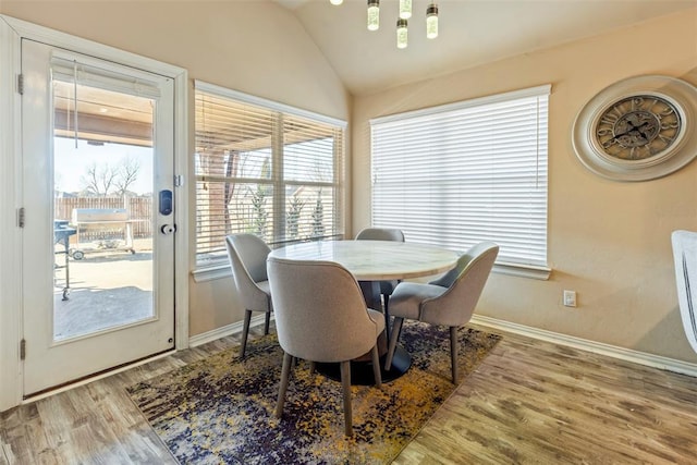 dining area with baseboards, lofted ceiling, and wood finished floors