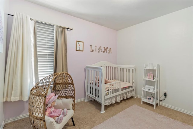 carpeted bedroom featuring a nursery area and baseboards