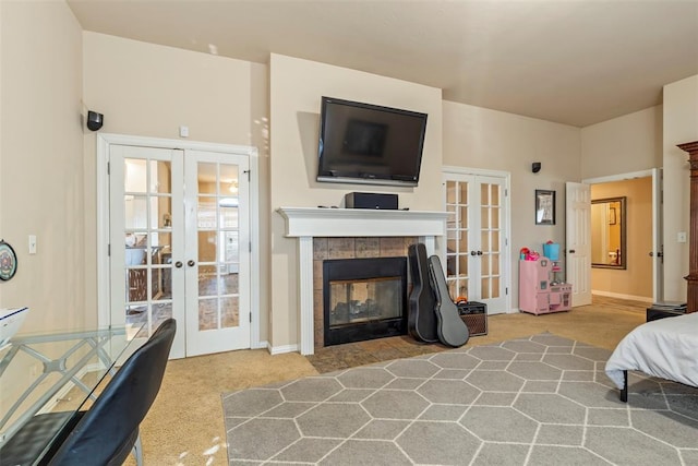 carpeted bedroom with french doors, baseboards, and a tile fireplace