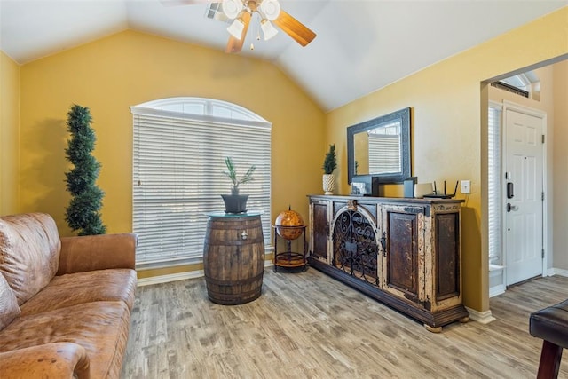 living room featuring vaulted ceiling, wood finished floors, baseboards, and ceiling fan