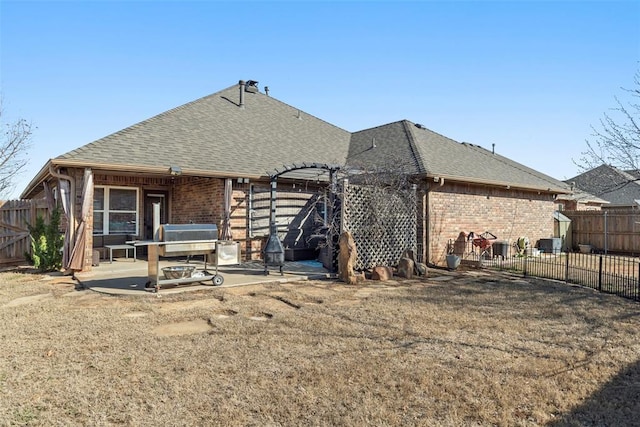 back of property with a pergola, a shingled roof, fence private yard, a patio area, and brick siding