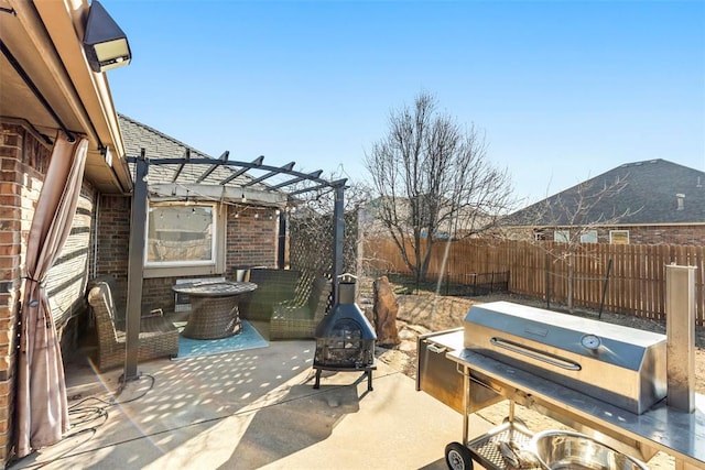 view of patio featuring grilling area, a fire pit, a fenced backyard, and a pergola