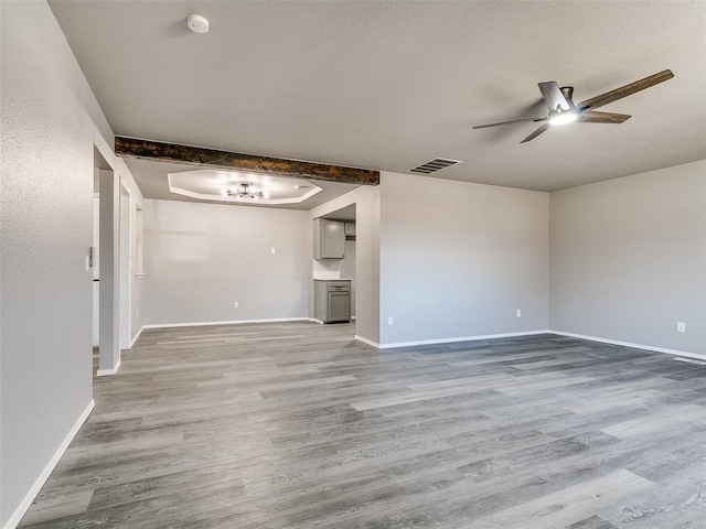 unfurnished living room with visible vents, baseboards, wood finished floors, a textured ceiling, and a ceiling fan