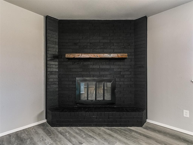 details with a fireplace, a textured ceiling, baseboards, and wood finished floors