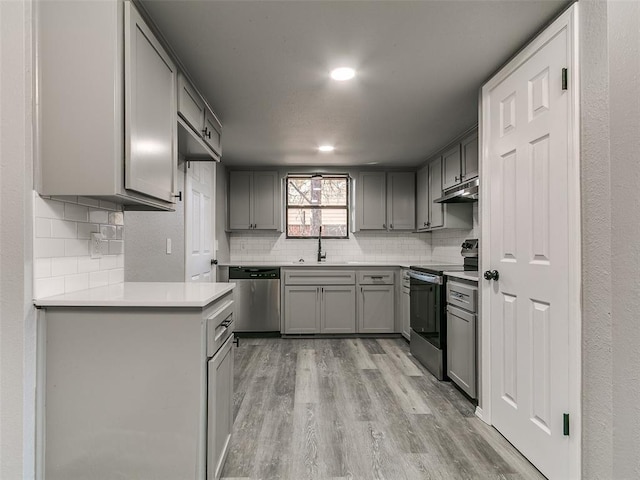 kitchen featuring gray cabinets, appliances with stainless steel finishes, light wood-style floors, and a sink