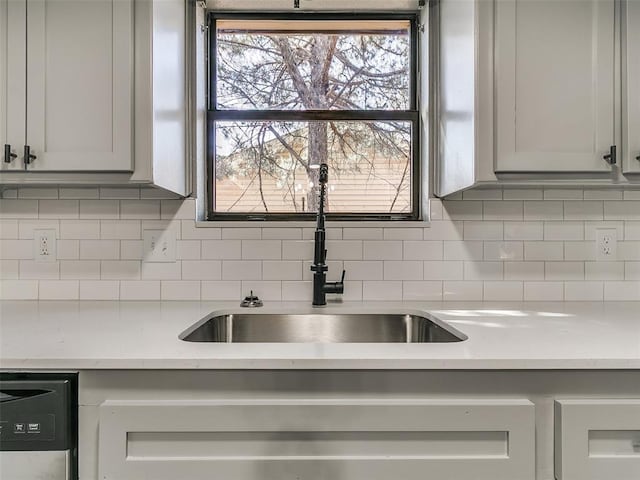 kitchen featuring a sink, tasteful backsplash, dishwasher, and light countertops