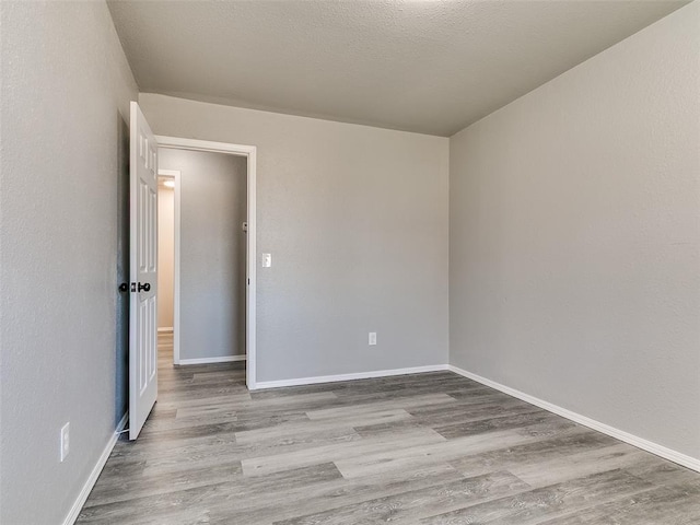 empty room featuring baseboards, a textured ceiling, and wood finished floors