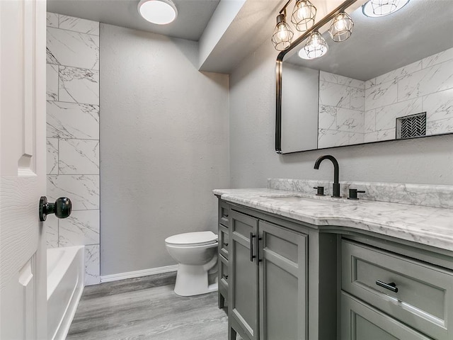 full bathroom with toilet, wood finished floors, baseboards, bathtub / shower combination, and vanity