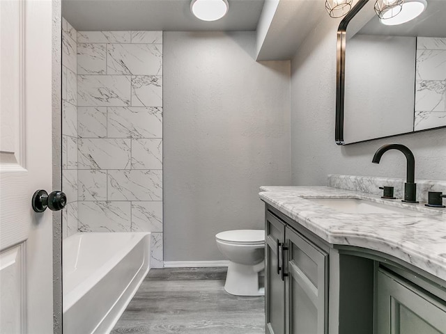 bathroom featuring baseboards, toilet, shower / tub combination, wood finished floors, and vanity