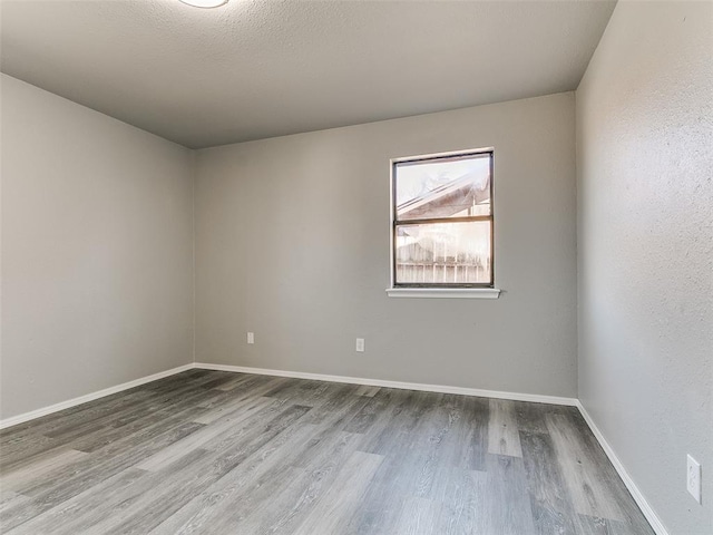 unfurnished room with wood finished floors, baseboards, and a textured ceiling