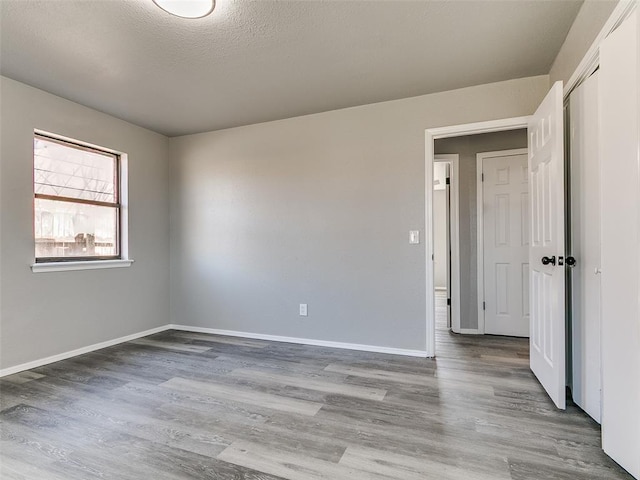 spare room with wood finished floors, baseboards, and a textured ceiling