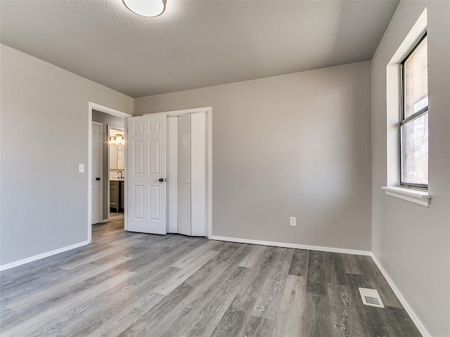 unfurnished bedroom with wood finished floors, visible vents, and baseboards