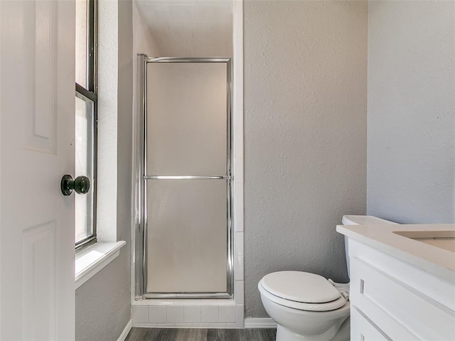 full bath featuring wood finished floors, a shower stall, toilet, and a textured wall