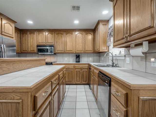 kitchen with tile countertops, visible vents, appliances with stainless steel finishes, and a sink