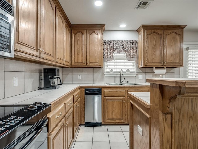 kitchen with visible vents, black range with electric cooktop, tile countertops, light tile patterned floors, and a sink